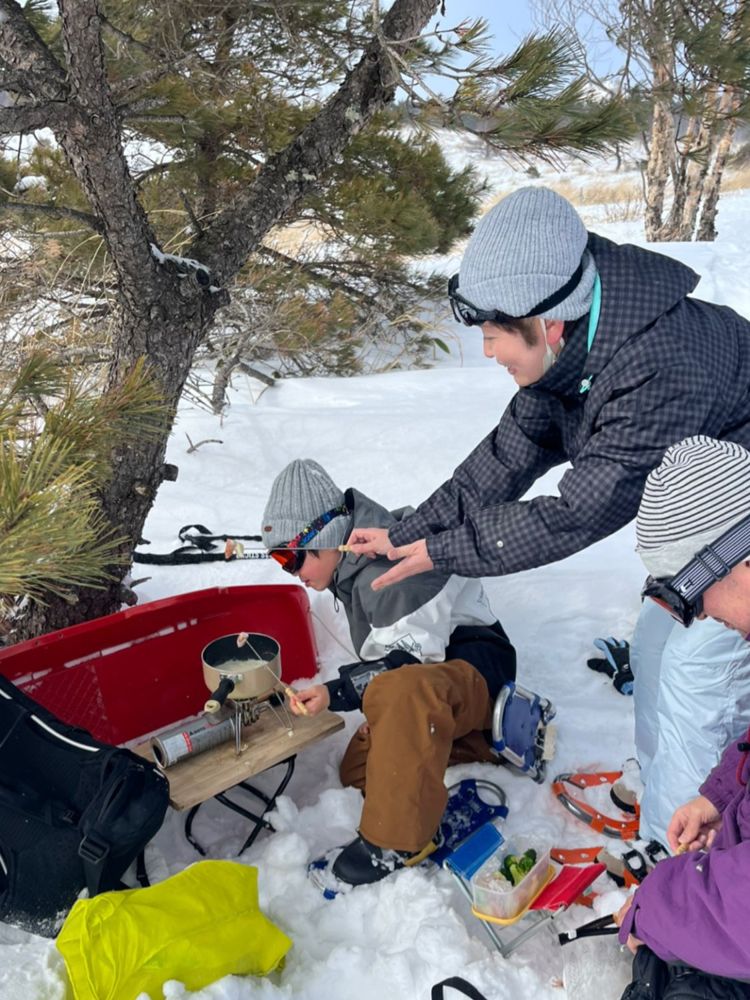 A family sharing a hot lunch cooked on a stove in the snow