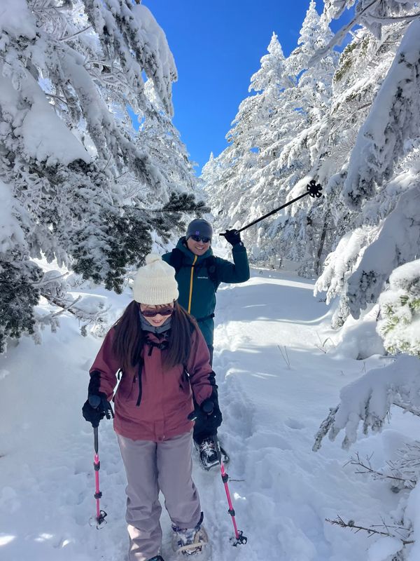 Snowshoers walking a snowy forest trail under rime-covered branches